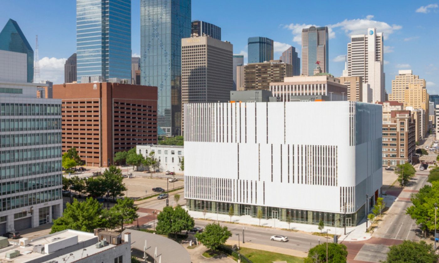 A Dallas County government facility with a white louvered facade against the downtown Dallas skyline