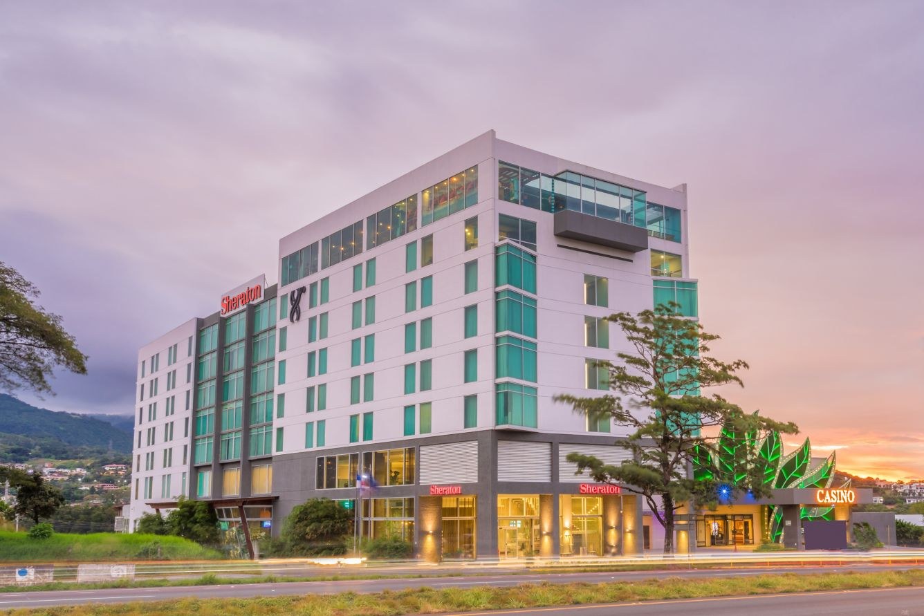 Exterior view of the Sheraton San Jose Hotel in Escazú, Costa Rica at dusk, with illuminated casino signage